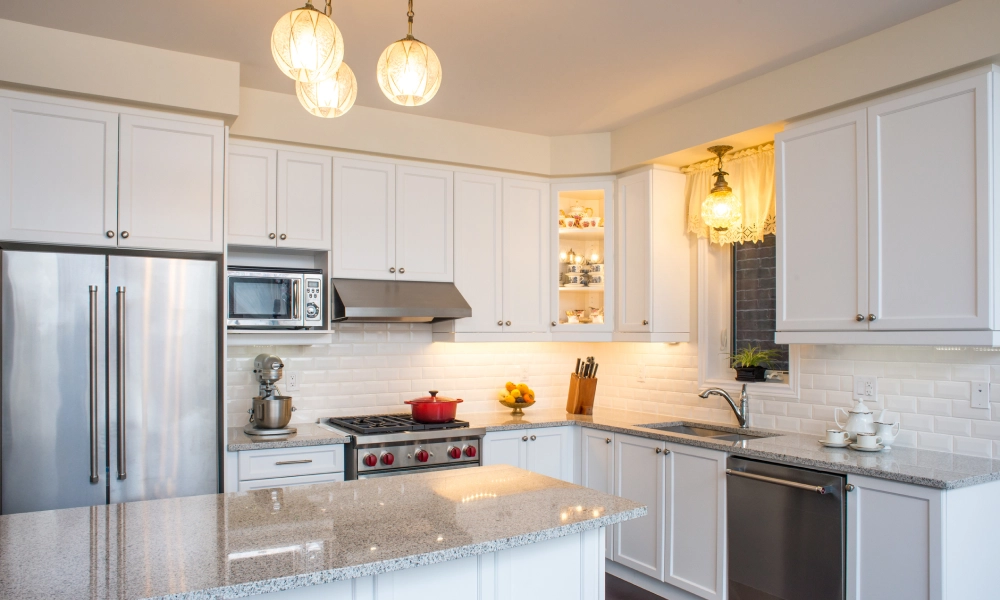Modern kitchen with white cabinetry and marble countertops.