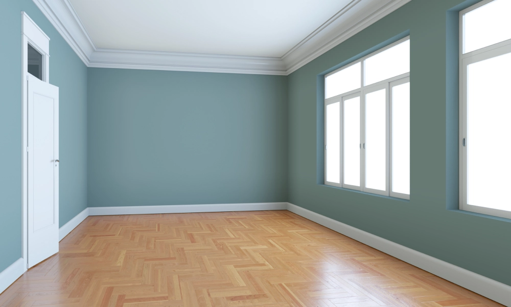 Empty room with light wood flooring and large window letting in natural light.