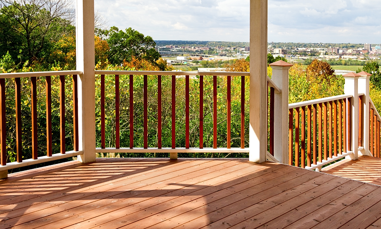 Spacious wooden porch with scenic suburban view and greenery.