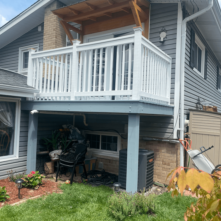 A raised wooden porch with white railings on a house exterior.